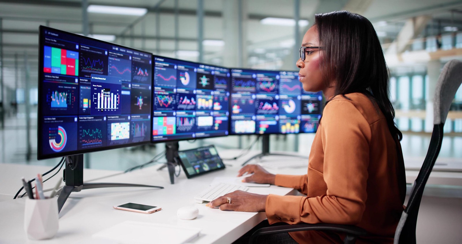 Technicienne devant plusieurs tableaux de bord de supervision
